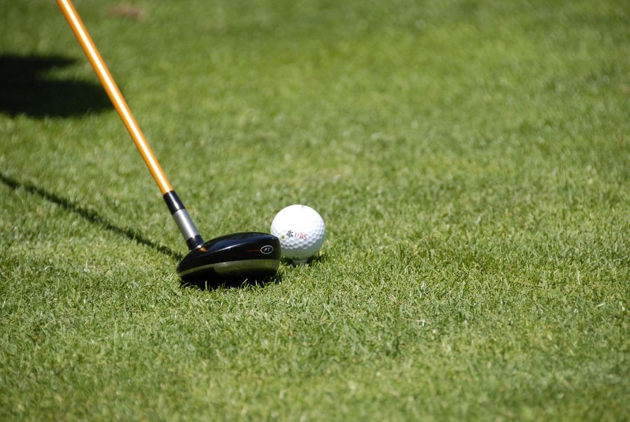 Ein Golfschläger liegt auf dem grünen Rasen neben einem Golfball mit UBS-Logo.